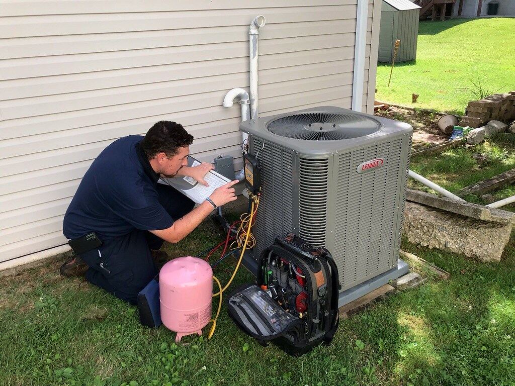 Technician performing commercial facilities maintenance on rooftop HVAC unit El Paso TX